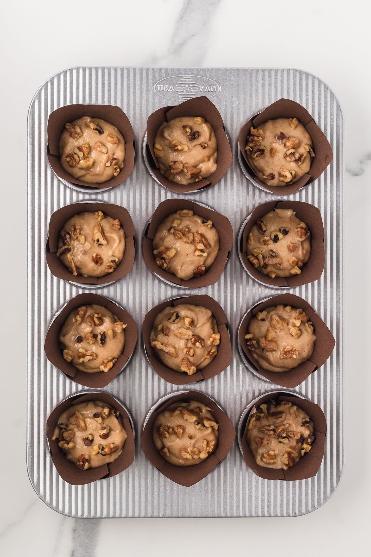 Banana bread muffin batter in brown tulip liners