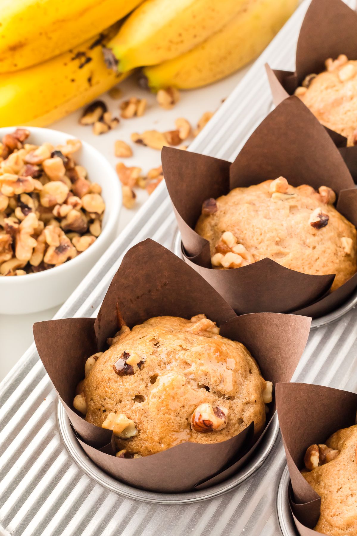 Banana bread muffins in tulip liners with bananas and walnuts