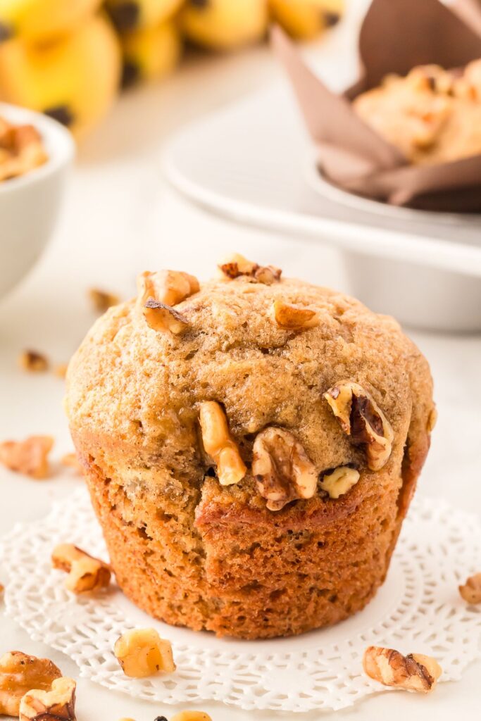 Banana bread muffin topped with walnuts on a doily