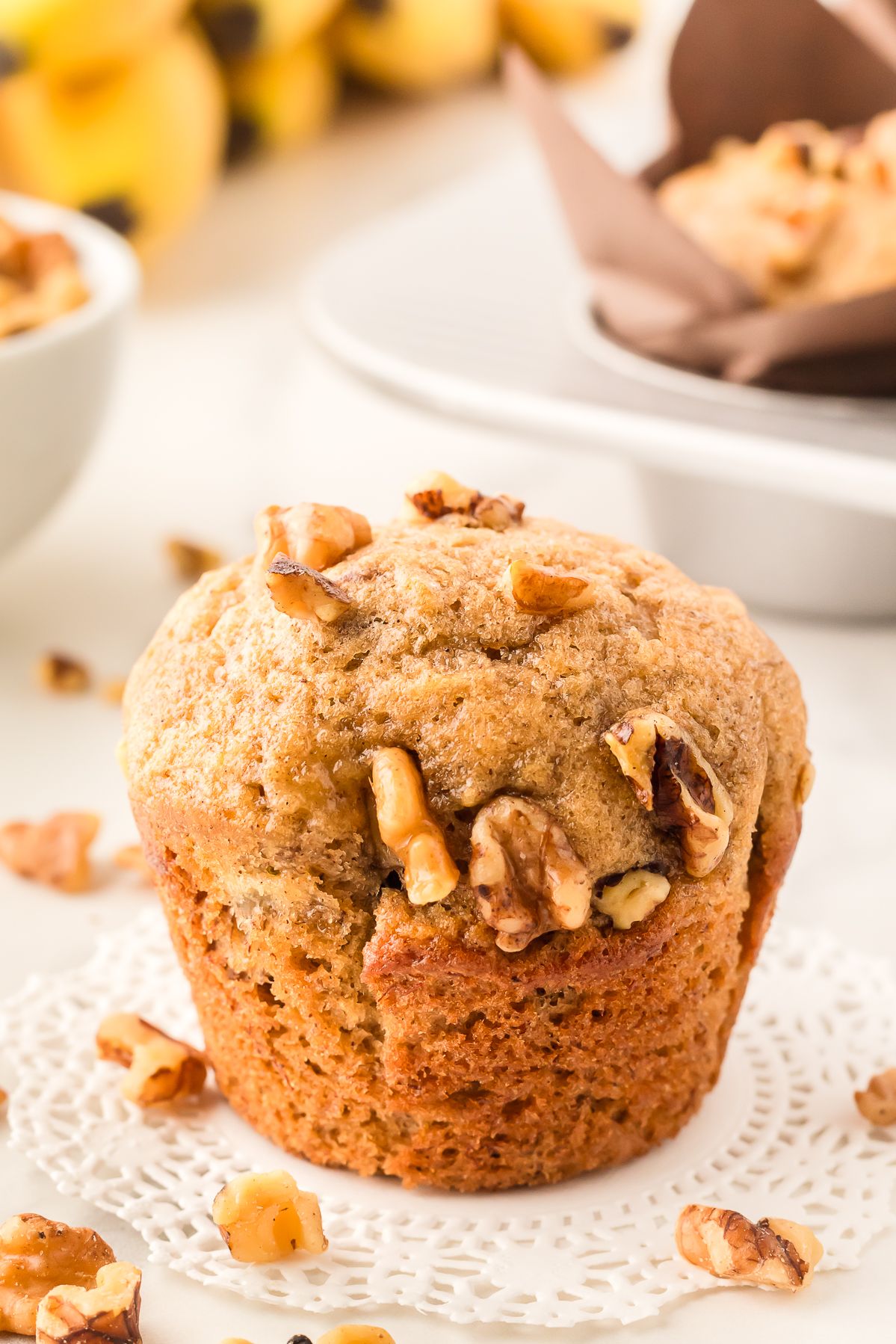 Banana bread muffin topped with walnuts on a doily