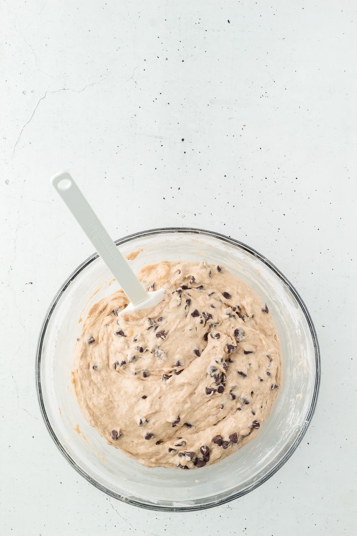 Banana chocolate chip muffin batter in a glass bowl