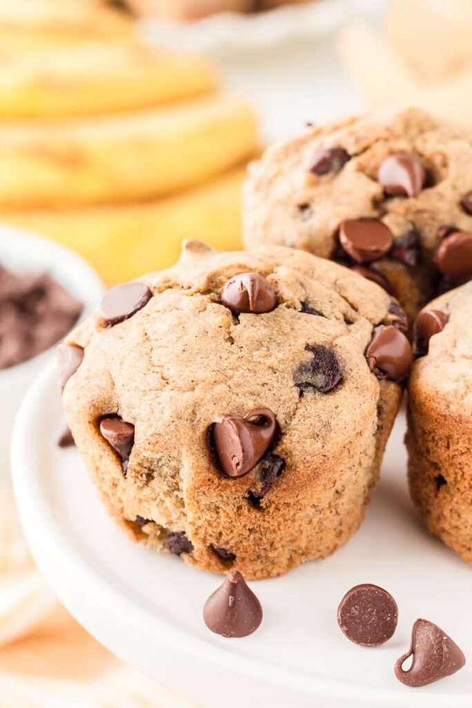 Banana chocolate chip muffin on a cake stand with chocolate chips