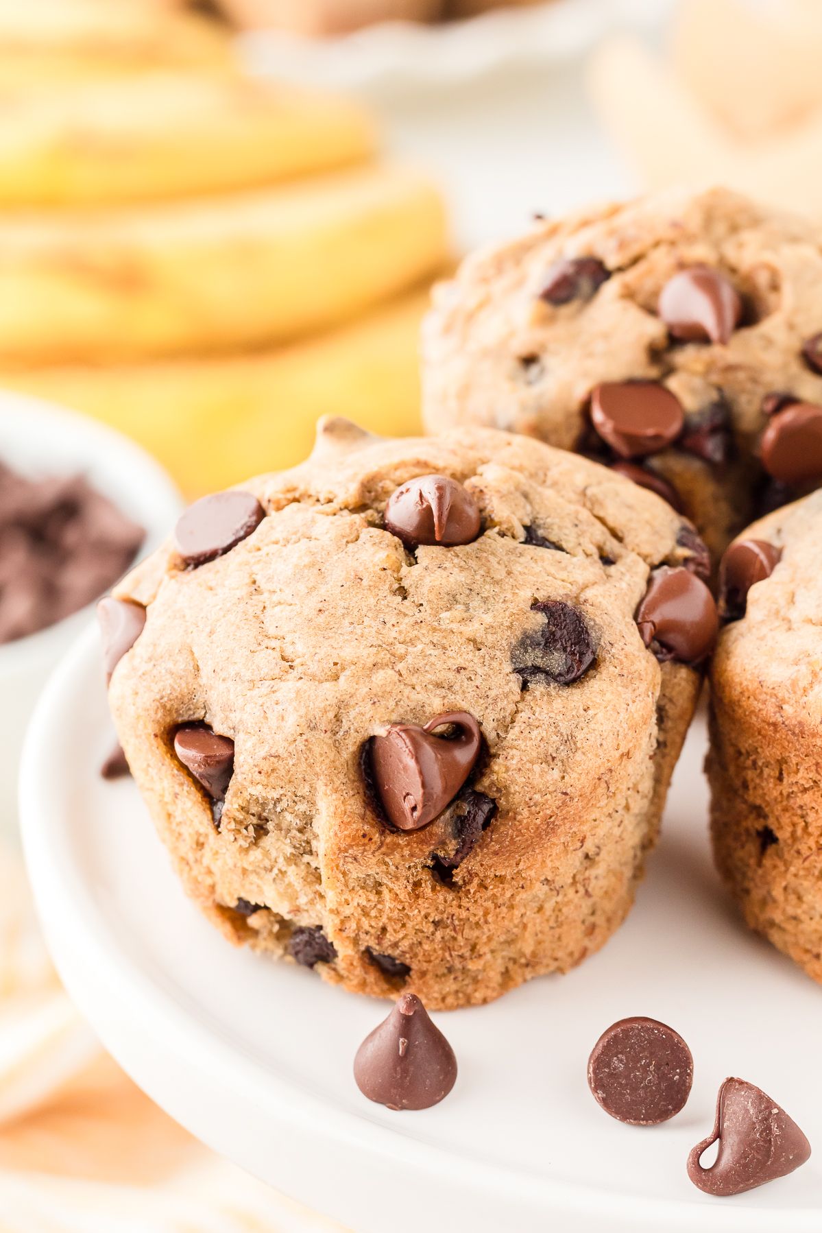 Banana chocolate chip muffin on a cake stand with chocolate chips