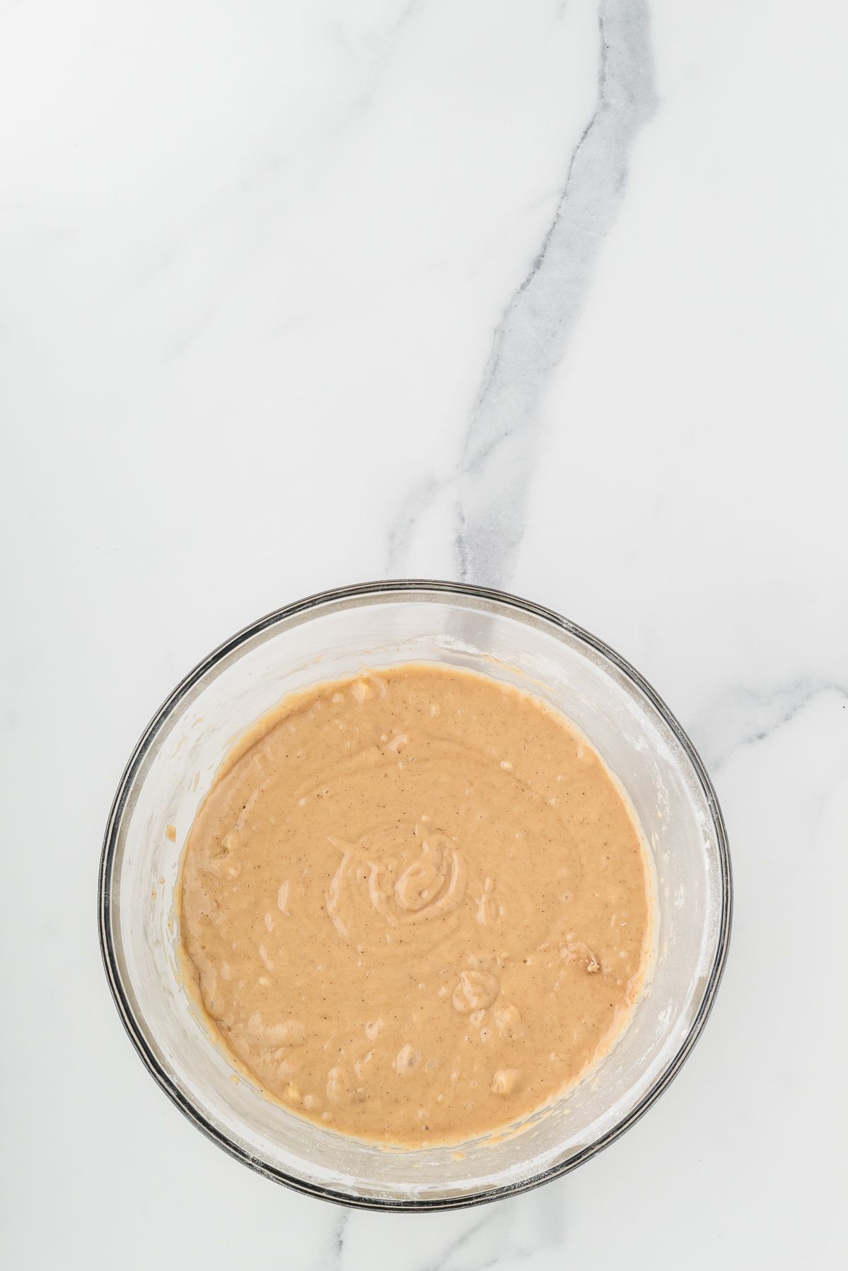 Banana muffin batter in a glass mixing bowl