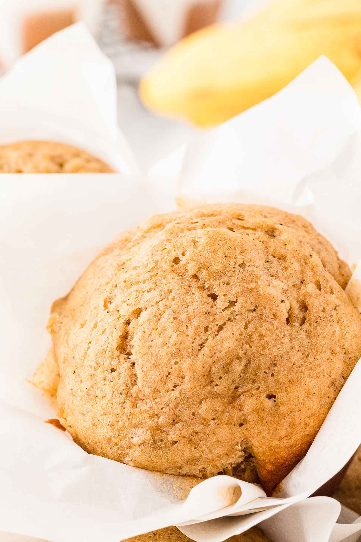Close up of a domed banana muffin in a parchment liner