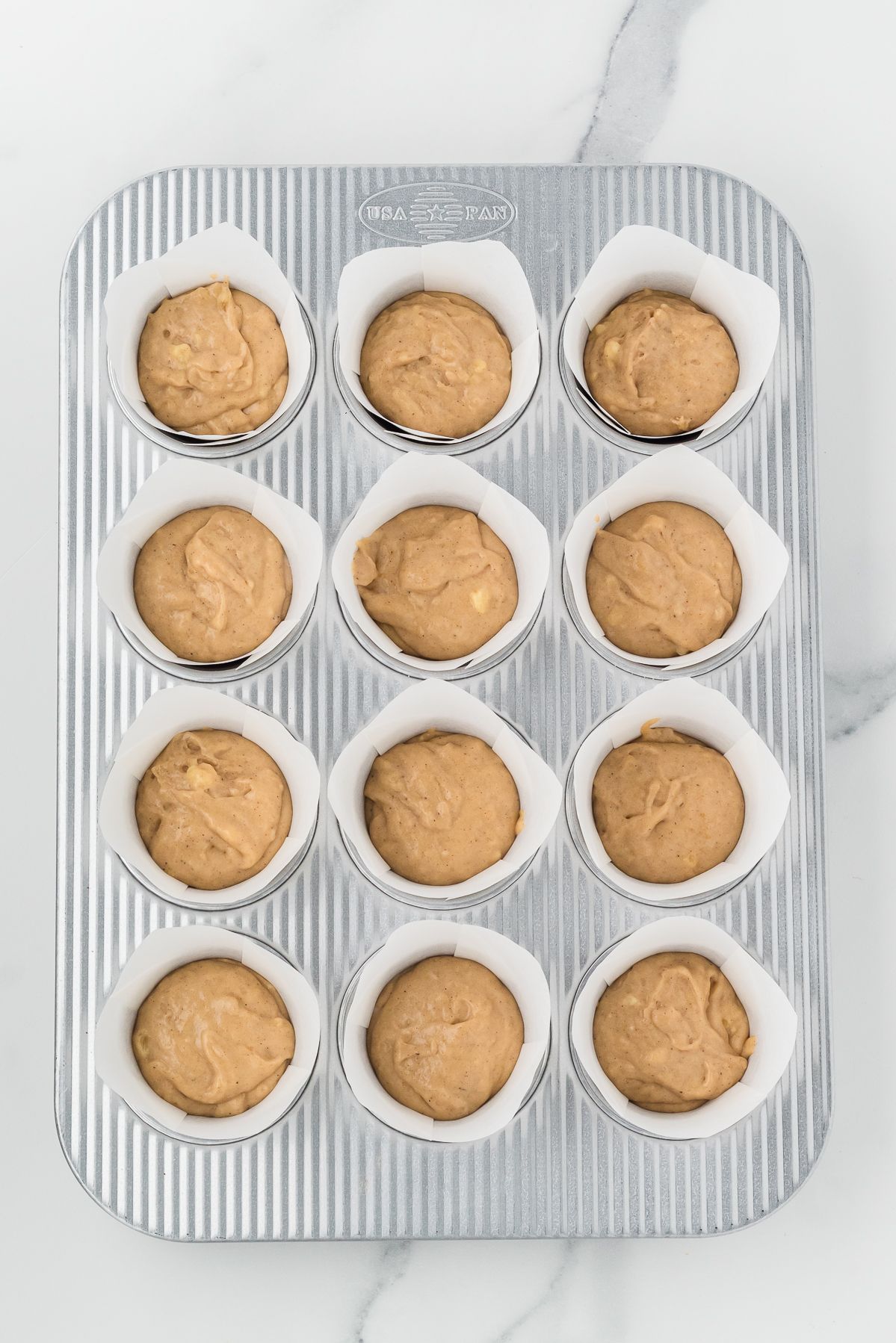 Banana muffin batter in a tulip lined muffin tin