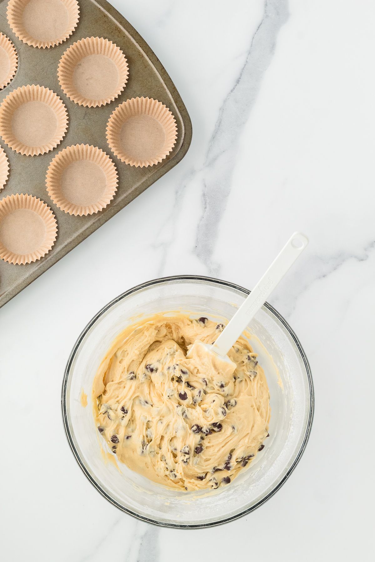 Chocolate chip muffin batter in a glass mixing bowl