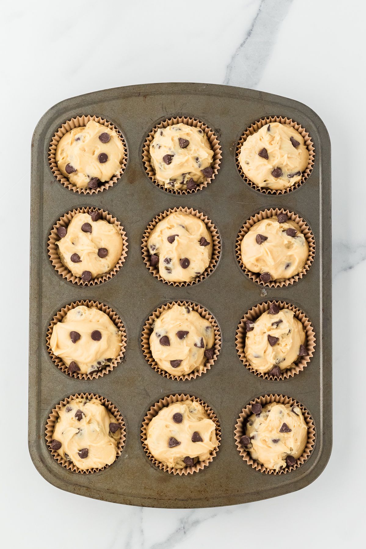 Chocolate chip muffin batter in a lined muffin tin