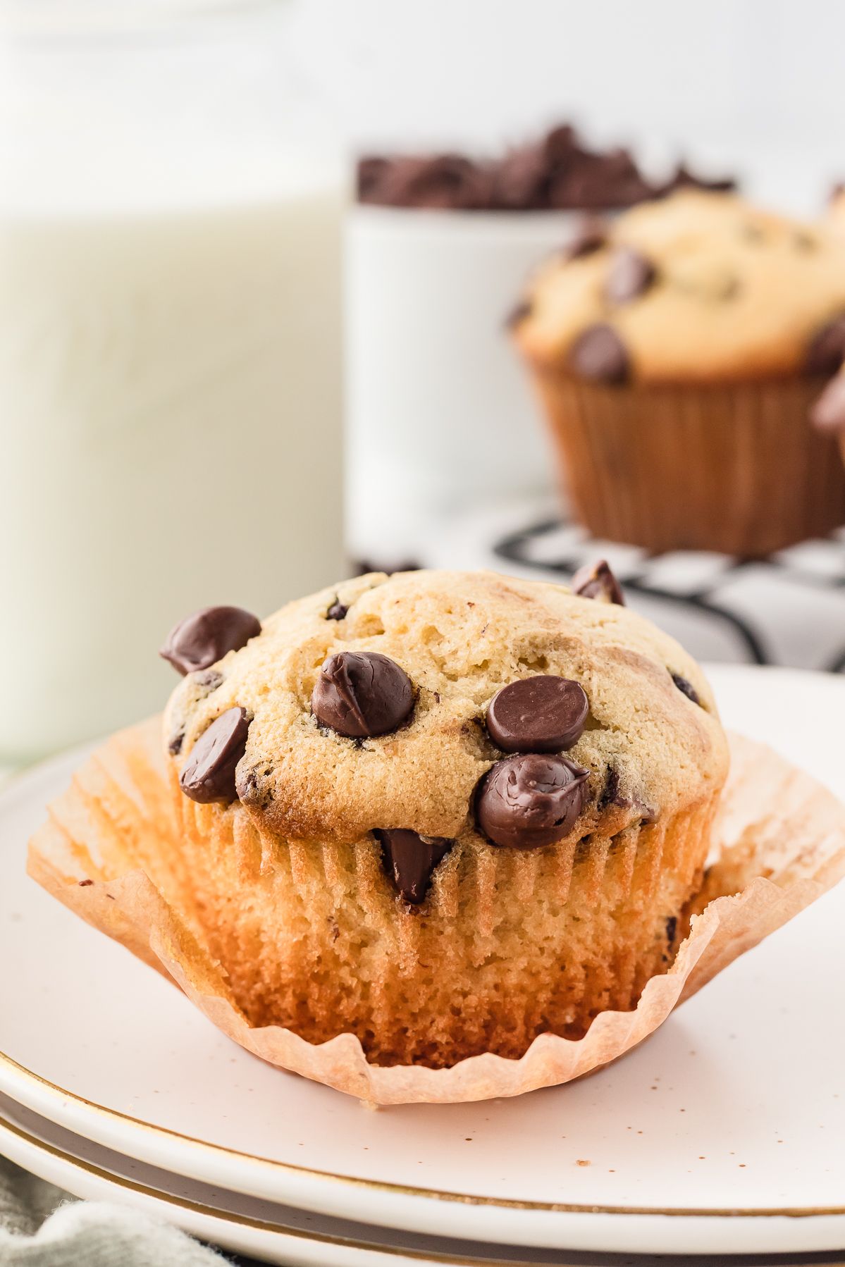 Chocolate chip muffin on a plate with a glass of milk