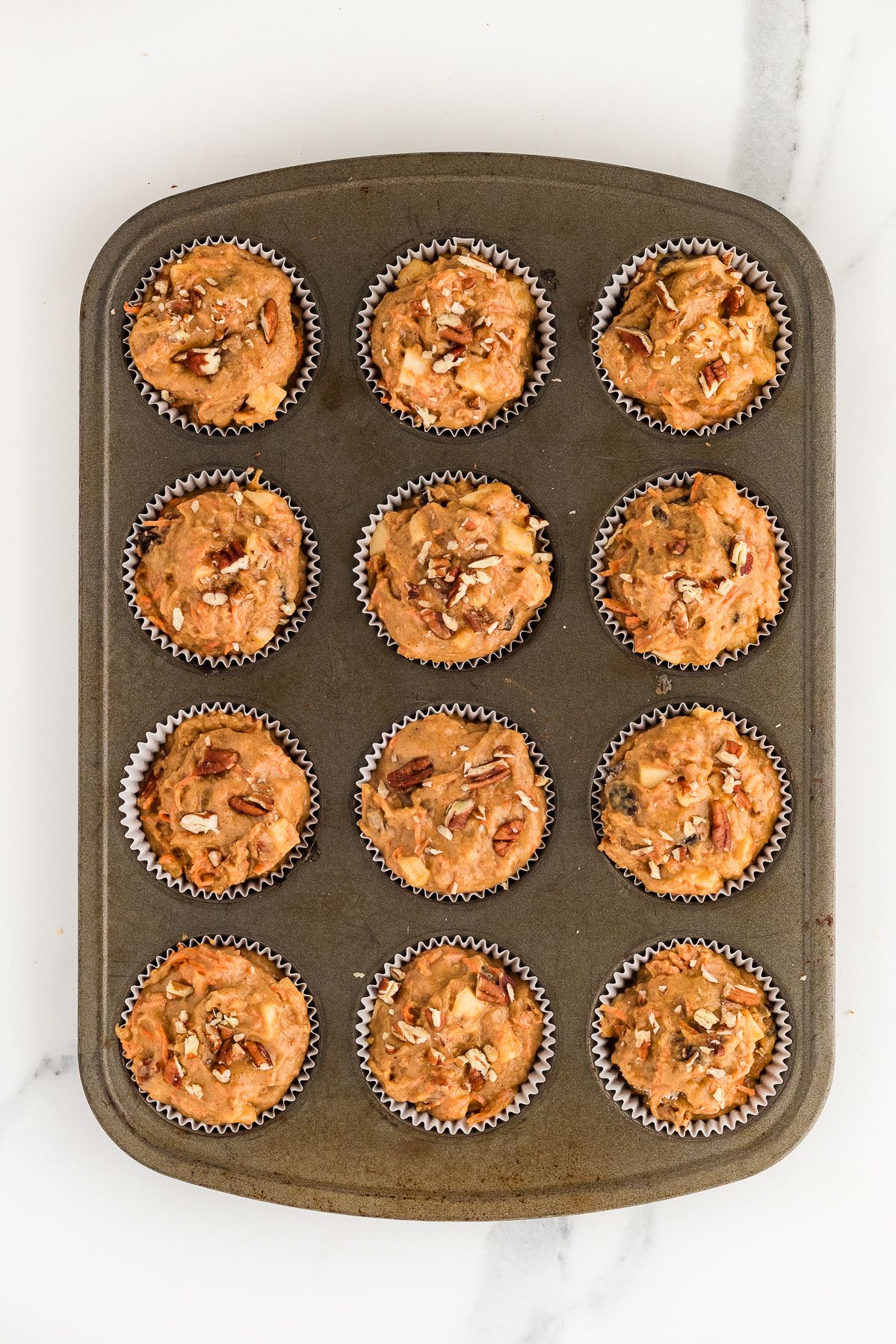 Gluten free morning glory muffin batter in a muffin tin