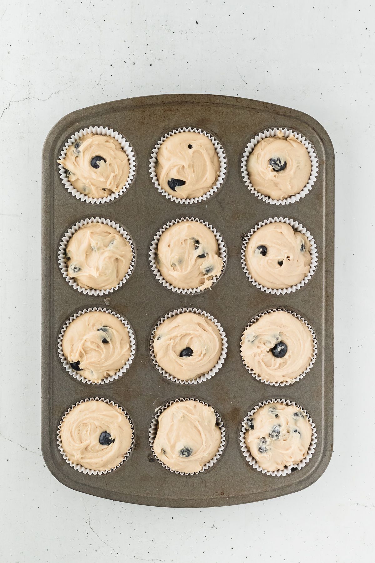 Healthy blueberry muffin batter in a lined muffin tin