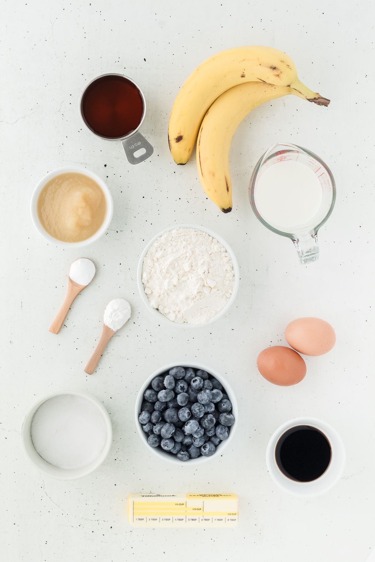 Ingredients for healthy blueberry muffins: blueberries, banana, applesauce, maple syrup, flour and eggs