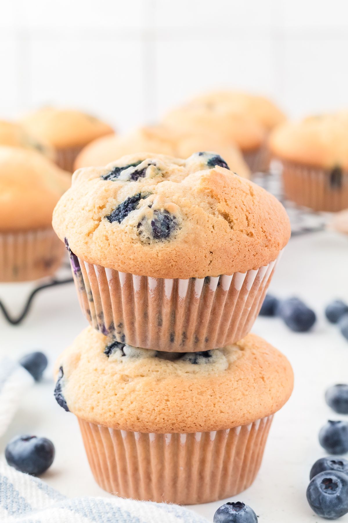 Two healthy blueberry muffins stacked with fresh blueberries