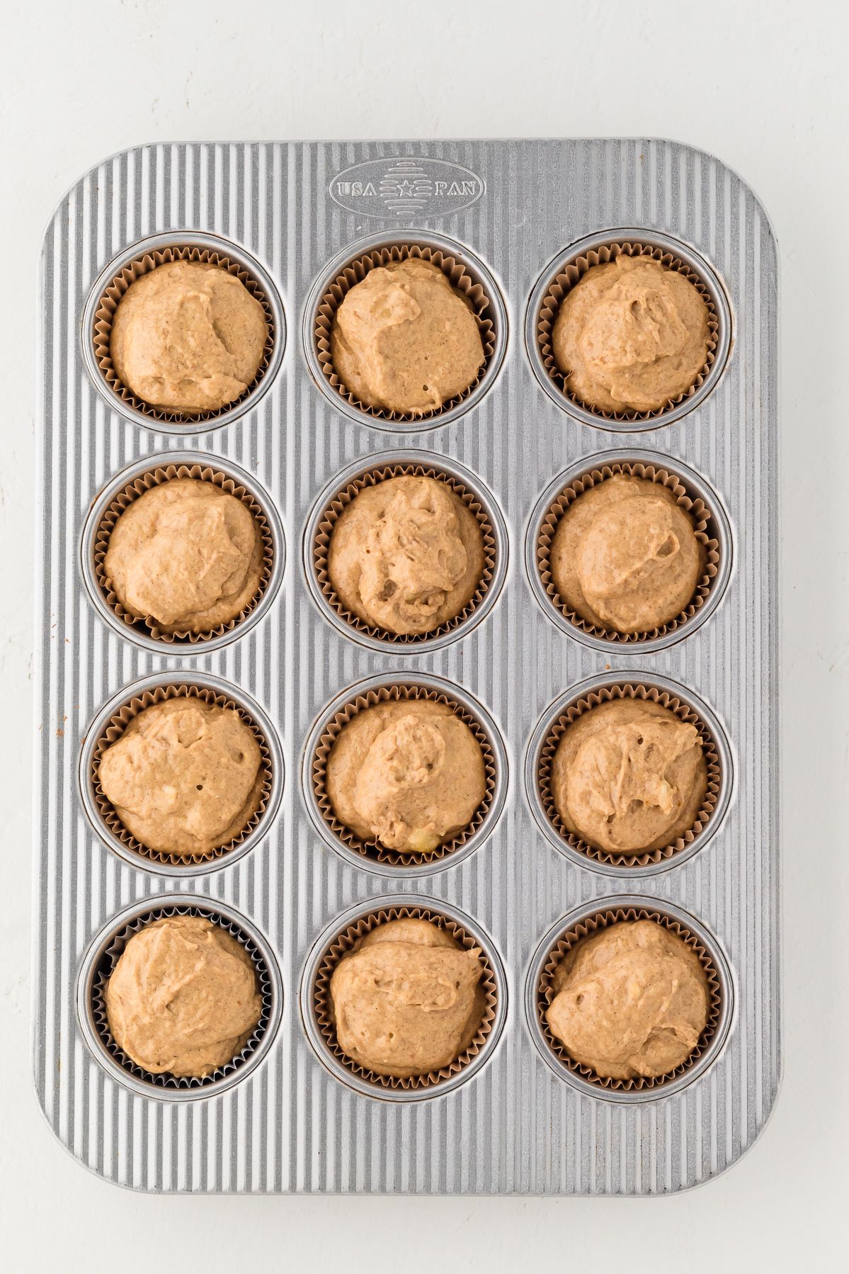 Healthy pumpkin muffin batter in a lined muffin tin