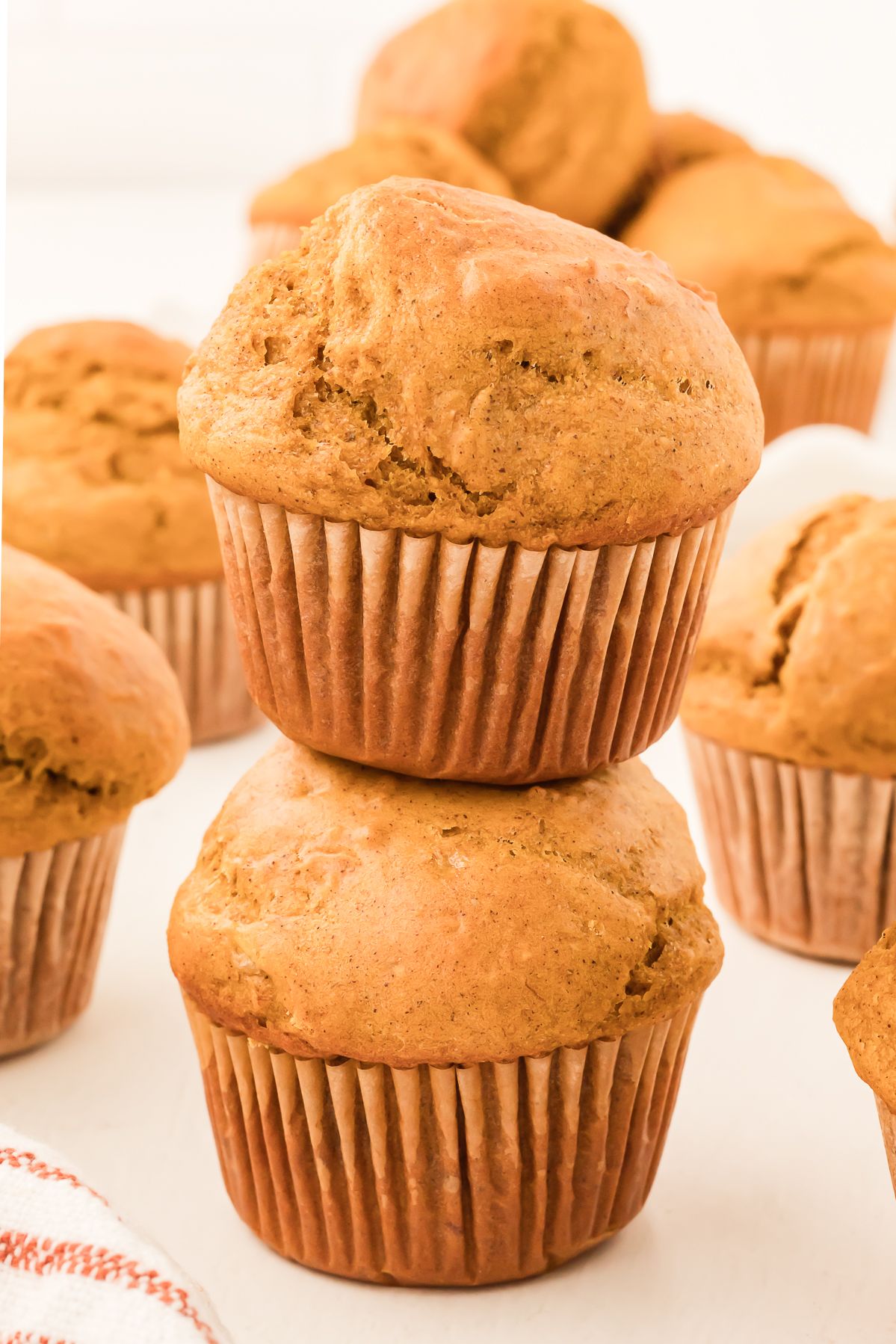Two healthy pumpkin muffins stacked on a white surface
