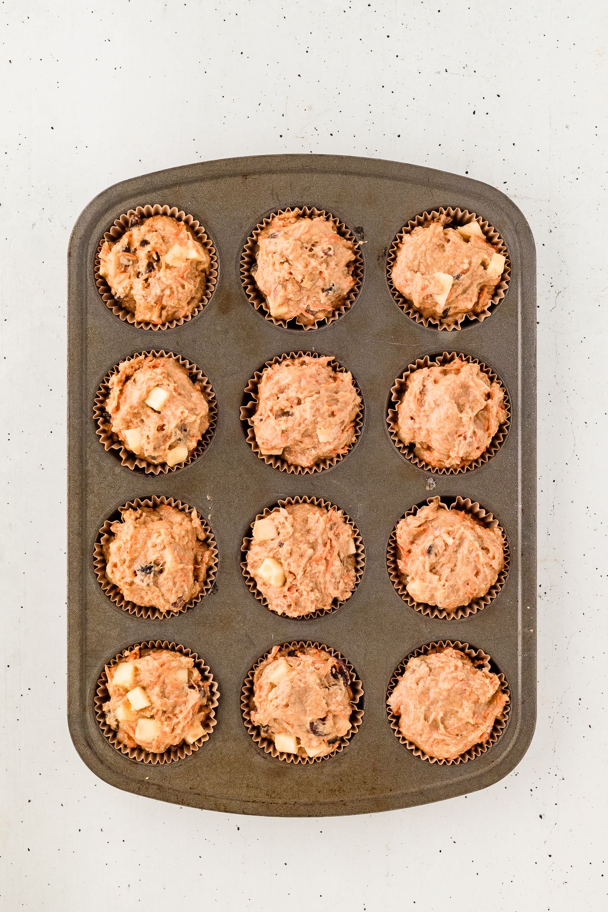 Morning glory muffin batter in a muffin tin
