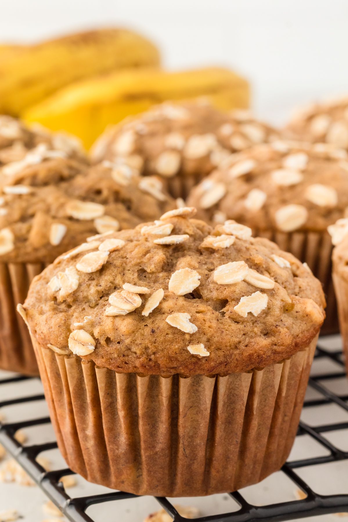 Banana oatmeal muffins on a cooling rack with bananas