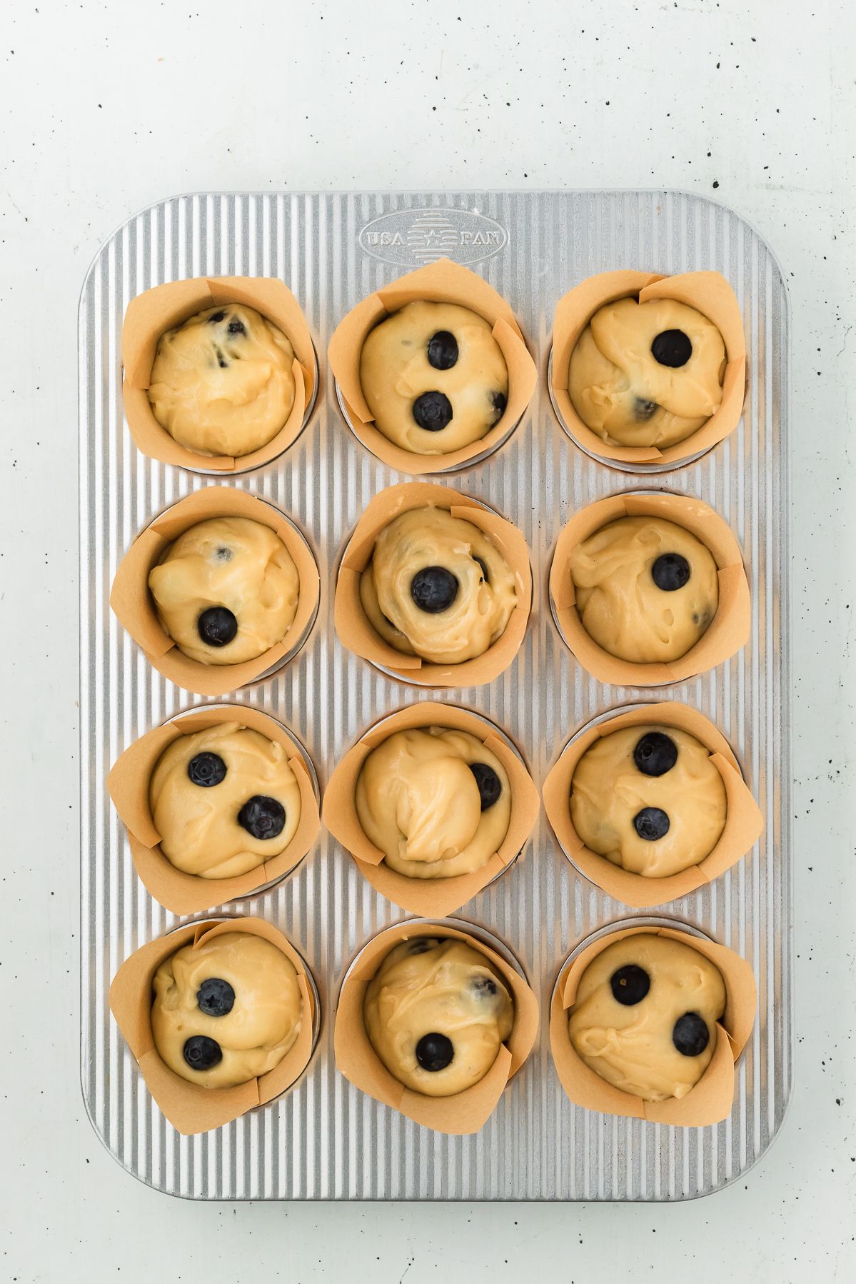 Lemon blueberry muffin batter in parchment lined muffin tin