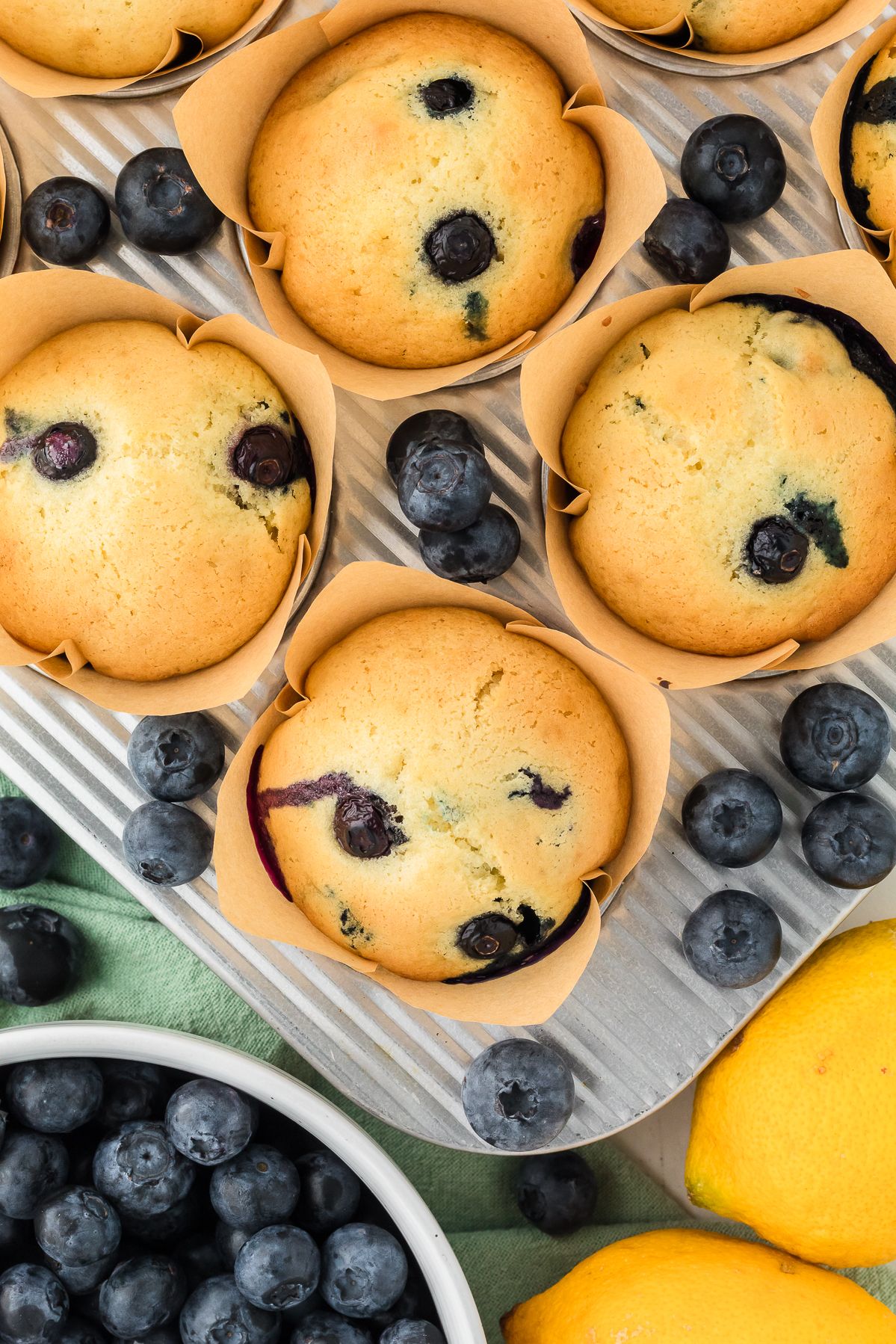 Overhead view of lemon blueberry muffins with fresh blueberries and lemon