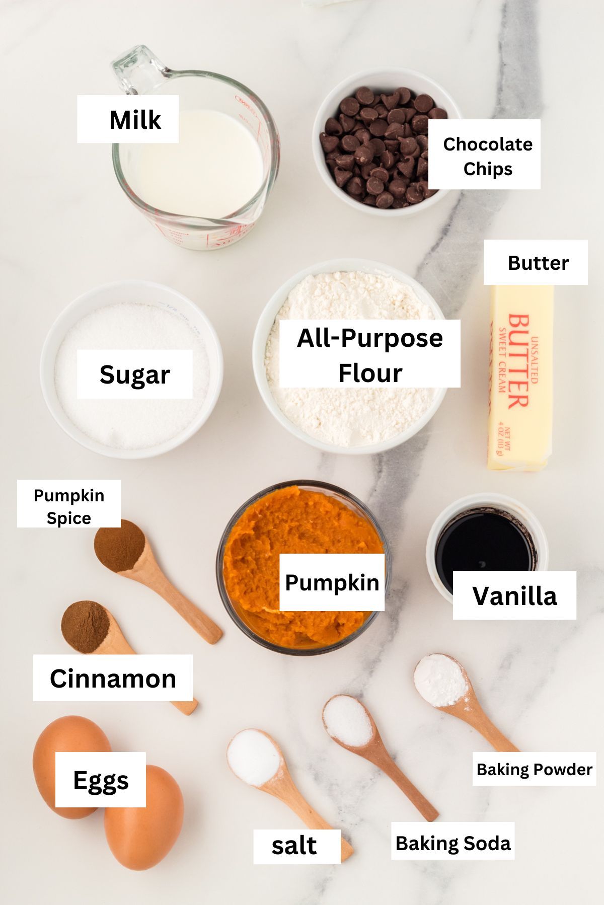 Labeled ingredients for pumpkin chocolate chip muffins: pumpkin puree, flour, sugar, butter, milk, eggs, spices and chocolate chips